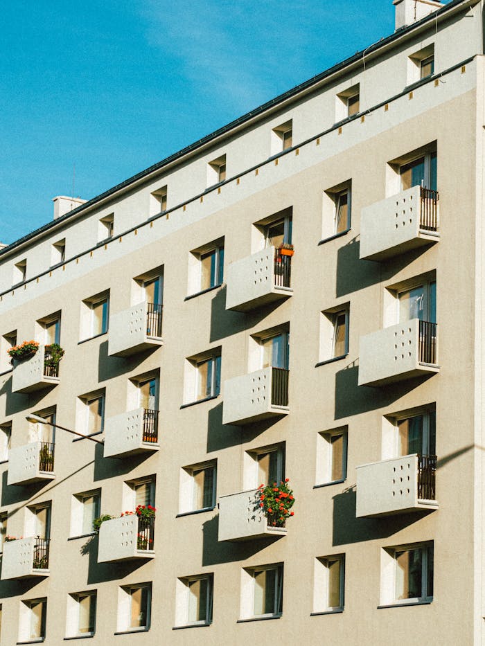 From below exterior of contemporary residential building with symmetric windows and balconies against cloudless blue sky